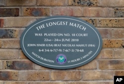 FILE - This Tuesday, July 4, 2017 file photo shows a plaque at the Wimbledon Tennis Championships in London, noting the site of John Isner's record-breaking 70-68 fifth-set victory over Nicolas Mahut in 2010. The All England Club said Friday Oct. 19, 2018