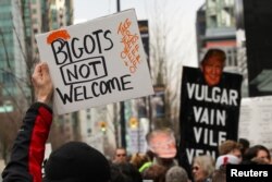 FILE - Protesters hold signs outside the Trump International Hotel and Tower during its grand opening in Vancouver, British Columbia, Feb. 28, 2017.