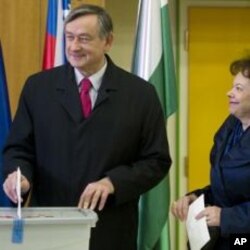 Slovenia's president Danilo Turk, left, casts his ballot as his wife Barbara Miklic, right, looks on at a polling station in Ljubljana, December 4, 2011.
