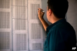 FILE - Bahzad Farhan Murad points to a list of missing and killed Yazidis to The Associated Press in the small office where he collects evidence on Islamic State crimes against Yazidis, in Dohuk, Iraq, May 22, 2016.