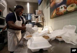 Tony Mertin packages hot meals at the Chef Creole restaurant at Miami International Airport, Jan. 15, 2019, in Miami.