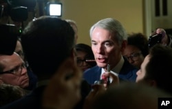 Reporters gather around Sen. Rob Portman, R-Ohio, on Capitol Hill in Washington, Dec. 15, 2017, as they ask questions on the progress of an agreement on a sweeping overhaul of the nation's tax laws.