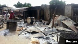 Residents stand in front of destroyed properties and houses following an attack in the northeast Nigerian village of Kawuri, Jan. 28, 2014. 
