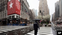 A man crosses the street in front of Macy's, Monday, March 23, 2020 in New York. Macy's stores nationwide are closed due to the coronavirus. 