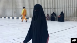 FILE - A veiled woman walks in Mecca, Saudi Arabia, where society is governed by a mix of ancient customs and conservative interpretations of Islam. Most women cover their faces and by law must wear long, flowing black abayas in public. 