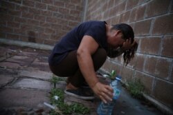 A migrant from El Salvador who sought asylum in the U.S. and is waiting for her date in court in order to return to the U.S. washes her hair outside a Mexican immigration office where migrants have set up camp in Matamoros, Mexico, Aug. 4, 2019.