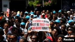 FILE - Eritrean refugees hold placards during a rally in support of a recent U.N. report that accused Eritrean leaders of committing crimes against humanity, outside the E.U. offices in Ramat Gan, Israel, June 21, 2016. 