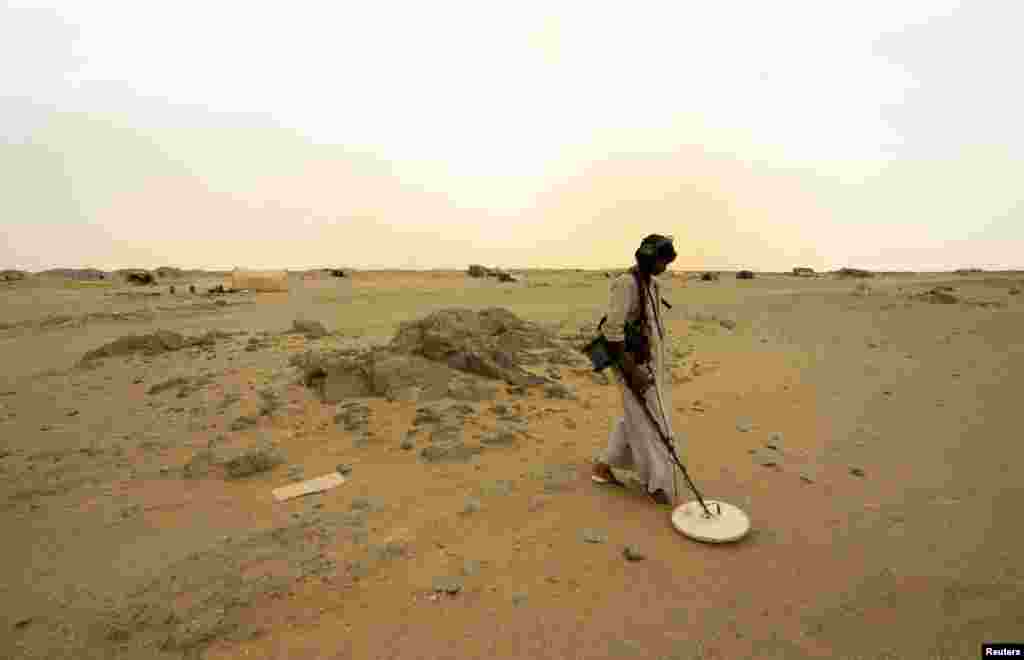 Seorang pekerja tambang emas menggunakan detektor di kota Al-Ibedia, kawasan Sungai Nil, Sudan.