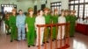 Doan Van Vuon (standing, 4th L), Doan Van Quy (standing, 2nd L) and Doan Van Sinh (standing, 3rd R) stand with policemen in front of the court dock to hear a verdict in Hai Phong, April 5, 2013, photo provided by the Vietnam News Agency (VNA).
