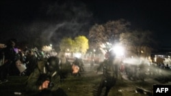 FILE - Law enforcement officers pepper spray freelance photographer Tim Evans, left, as he identifies himself as a working journalist outside the Brooklyn Center police station in Brooklyn Center, Minnesota, April 16, 2021. 