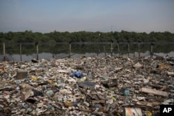 FILE - In this May 15, 2014 photo, trash floats on a polluted water channel that flows into the Guanabara Bay in Rio de Janeiro, Brazil.