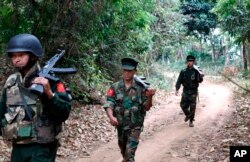 FILE - Kachin Independence Army fighters walk in a jungle path from Mu Du front line to Hpalap outpost in an area controlled by the Kachin rebels in northern Kachin state, Myanmar, March 17, 2018.