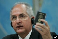 FILE - Caracas' Mayor Antonio Ledezma holds up a small copy of Venezuela's constitution as he addresses the Commission of External Relationships in Brazil's Senate in Brasilia, Oct. 27, 2009.