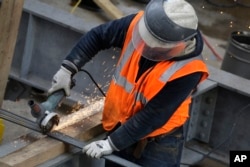 Sparks fly as a construction worker uses a grinder to cut through steel reinforcing bars, Feb. 1, 2016, in New York.