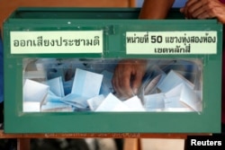 An election commission official holds a ballot paper from a ballot box while counting votes during a constitutional referendum vote at a polling station in Bangkok, Aug. 7, 2016.