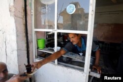 An Iraqi man distributes tea for people at a cafe in the destroyed Old City of Mosul, Iraq, Aug. 7, 2017.