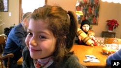 Syrian refugees Dania Khatib, 5, with her mother Mahasen Boshnaq, rear, holding her brother Mohammed, 1, sits in the home of their sponsoring family, Jan. 27, 2017, in Rutland, Vt. The Khatib family arrived in Rutland this month.