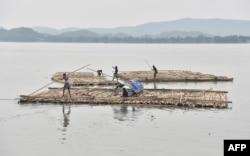 Vendors steer a bamboo pontoon along the Brahmaputra River in Guwahati, India, June 1, 2017.
