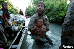 FILE - Rohingya refugees arrive to the Bangladeshi side of the Naf River after crossing the border from Myanmar, in Palang Khali, Bangladesh, Oct. 16, 2017.