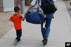 FILE - Three-year-old Jose Jr., from Honduras, is helped by a representative of the Southern Poverty Law Center as he is reunited with his father, July 10, 2018, in Phoenix.