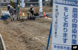 FILE - Workers clean a farm road during their decontamination work in Minamisoma, Fukushima prefecture, northeastern Japan, Feb. 24, 2016.