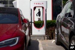 A security personnel riding a motorized platform moves past an electric vehicle charging station in Beijing, China, April 14, 2017.