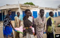 Women carry the body of a civilian killed in the center of Malakal, Upper Nile State in South Sudan, Jan. 21, 2014.