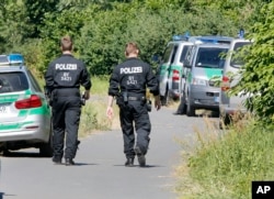 FILE - Police officers walk to the crime scene near the river Main, background, where a 17-year-old man from Afghanistan was shot the night before, in Wuerzburg, Germany, July 19, 2016.