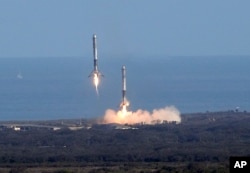 Two booster rockets from the Falcon 9 SpaceX Heavy, return for a landing at the Kennedy Space Center in Cape Canaveral, Fla., Feb. 6, 2018.