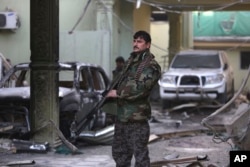 FILE - An Afghan security forces member stands guard at the Spanish Embassy after an attack in Kabul, Afghanistan, Dec. 12, 2015.