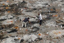 Rođaci ljudi koji su preminuli od koronavirusa prikupljaju pepeo sa mesta na kojima su žrtve kremirane, kao deo rituala u krematorijumu u Nju Delhiju, Indija.