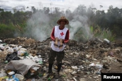 Venezuelan Charles Sanchez holds a pair of shoes after scraping on a garbage dump in the border city of Pacaraima, Brazil, April 15, 2019.
