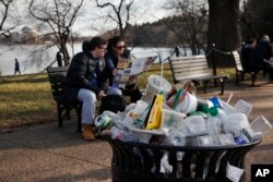 A trash can overflows as people site outside of the Martin Luther King Jr. Memorial by the Tidal Basin, Dec. 27, 2018, in Washington, during a partial government shutdown.