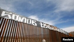A group of activists paints the U.S.-Mexico border wall between Ciudad Juarez and New Mexico as a symbol of protest against U.S. President Donald Trump's new immigration reform in Ciudad Juarez, Mexico, Feb. 26, 2017. The paint reads "We are workers."