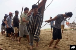 FILE - Vietnamese villagers move a fishing boat on shore in northern Thanh Hoa province, Vietnam, Sept. 14, 2017. A Ho Chi Minh City businessperson said the new president likely to bring little tangible change to their lives.