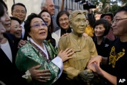 Former World War II "comfort woman" Yongsoo Lee, 89, of South Korea, stands by a statue of Haksoon Kim while looking at the "Comfort Women" monument after it was unveiled, Sept. 22, 2017, in San Francisco.