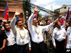 FILE - Cambodia's opposition leader Sam Rainsy, center, of the Cambodia National Rescue Party waves along with his party Vice President Kem Sokha, third from left, during a march in Phnom Penh, Cambodia, Sunday, March 30, 2014.