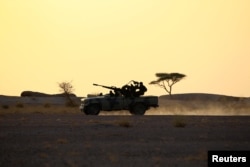 FILE - The Polisario Front soldiers drive a pick-up truck mounted with an anti-aircraft weapon during sunset in Bir Lahlou, Western Sahara, Sept. 9, 2016.