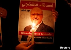 FILE - A protester holds a poster with a picture of slain Saudi journalist Jamal Khashoggi, outside Saudi Arabia's consulate in Istanbul, Turkey, Oct. 25, 2018.