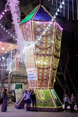Orang-orang mengambil foto di samping lentera Ramadhan tradisional yang disebut "fanous" menjelang bulan suci Ramadhan, di tengah pandemi COVID-19 di Kairo, Mesir, 8 April 2021. (Foto: REUTERS/Mohamed Abd El Ghany)