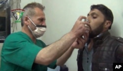 FILE - This video image from an anti-Bashar Assad activist group shows a Syrian man being treated with an inhaler in Kfar Zeita, north of Damascus, after what witnesses said was a chlorine gas attack, April 18, 2014.