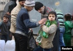 Civilians fill containers and bottles with water in a rebel-held besieged area of Aleppo, Syria, Dec. 10, 2016.