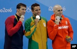 Men's 100-meter butterfly silver medalists, from left, United States' Michael Phelps, South Africa's Chad Le Clos and Hungary's Laszlo Cseh hold up their medals at the medal ceremony during swimming competitions at the 2016 Summer Olympics, Friday, Aug. 12, 2016, in Rio de Janeiro, Brazil.