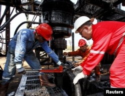 Men work at an oil pump in Lagunillas, Ciudad Ojeda, in the state of Zulia, Venezuela, March 20, 2015.