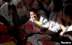 FILE - Mourners weep over the coffin of a Syrian journalist killed by the Islamic State militants on the frontline in Deir al-Zour, during a funeral in Kobani, Syria, Oct. 14, 2017.