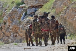FILE - Fighters with the Syrian Democratic Forces (SDF) patrol near the village of Baghuz in the Syrian countryside, March 20, 2019.