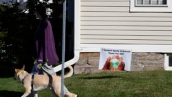A woman walks her dog past a sign supporting equity in schools, in Guilford, Conn., on Tuesday, Oct. 19, 2021. (AP Photo/Jessica Hill)