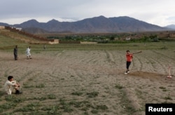 FILE - Afghan men play cricket on outskirt of Kabul, Afghanistan, May 15, 2017.