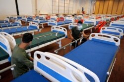 សមាជិកយោធាកម្ពុជារៀបចំគ្រែសម្រាប់អ្នកជំងឺកូវីដ១៩ នៅអគារក្នុងតំបន់កោះពេជ្រ រាជធានីភ្នំពេញ កាលពីថ្ងៃទី ១១ ខែមេសា ឆ្នាំ ២០២១។