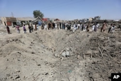 FILE - In this Monday, Aug. 1, 2016 file photo, Afghans look at a crater caused by a truck bombing, in Kabul, Afghanistan.
